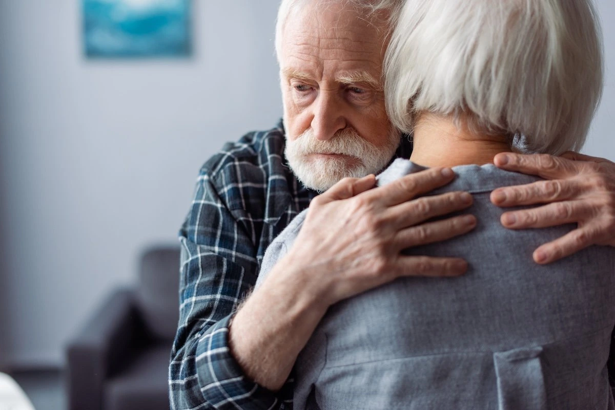 Älterer Mann mit Alzheimer wird liebevoll umarmt – Unterstützung bei Demenz